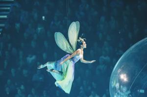 Eine als Libelle verkleidete Schauspielerin fliegt in die Arena